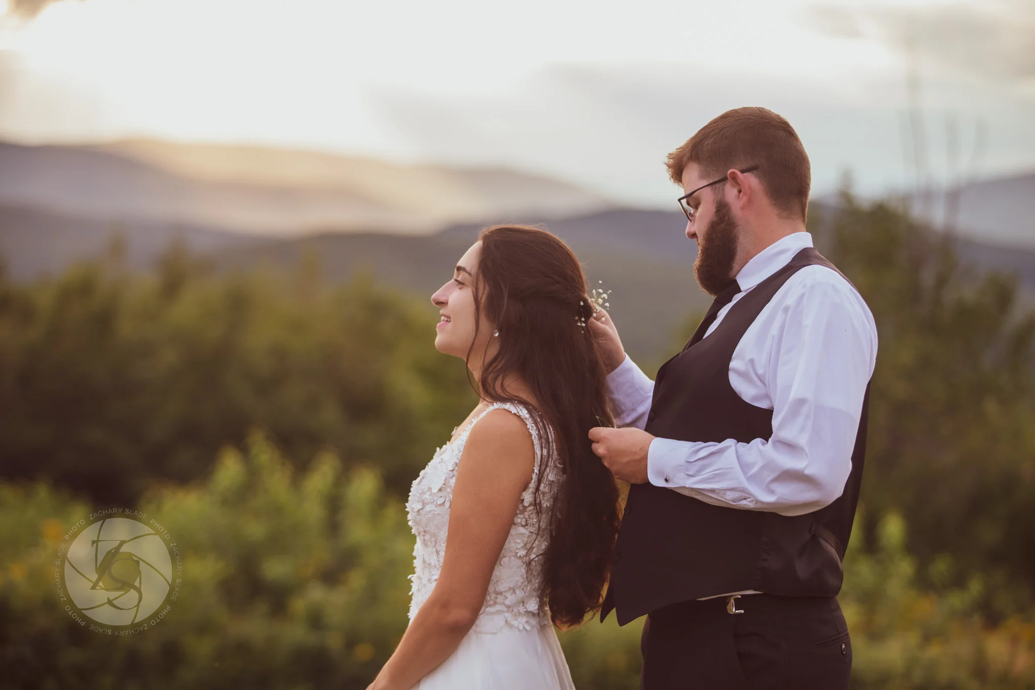 Groom placing flowers in bride's hair during Hartford Maine wedding morning